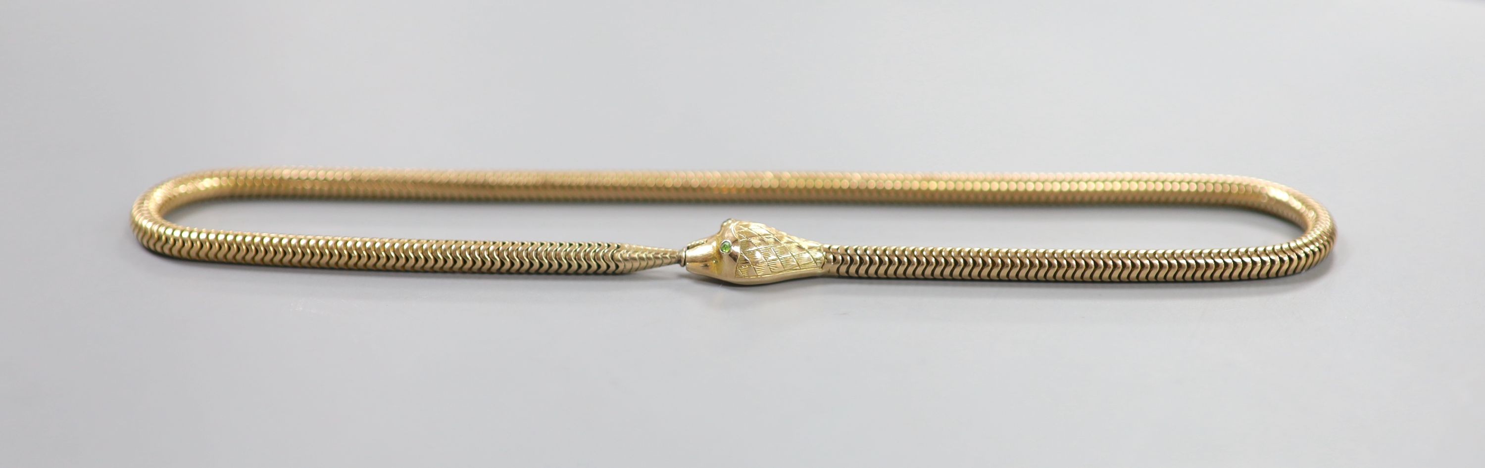 An Edwardian 9ct gold serpentine coil link serpent choker necklace, with green garnet set eyes, 36cm, gross 35 grams.